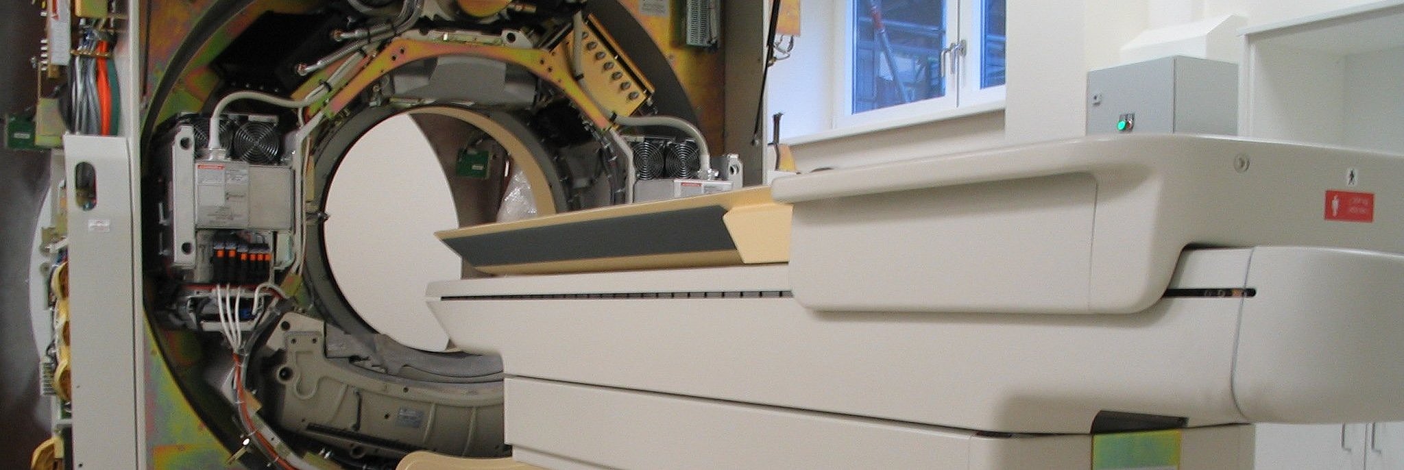 Offener Computertomograph mit ausfahrbarem Patientenbett in einem medizinischen Untersuchungsraum